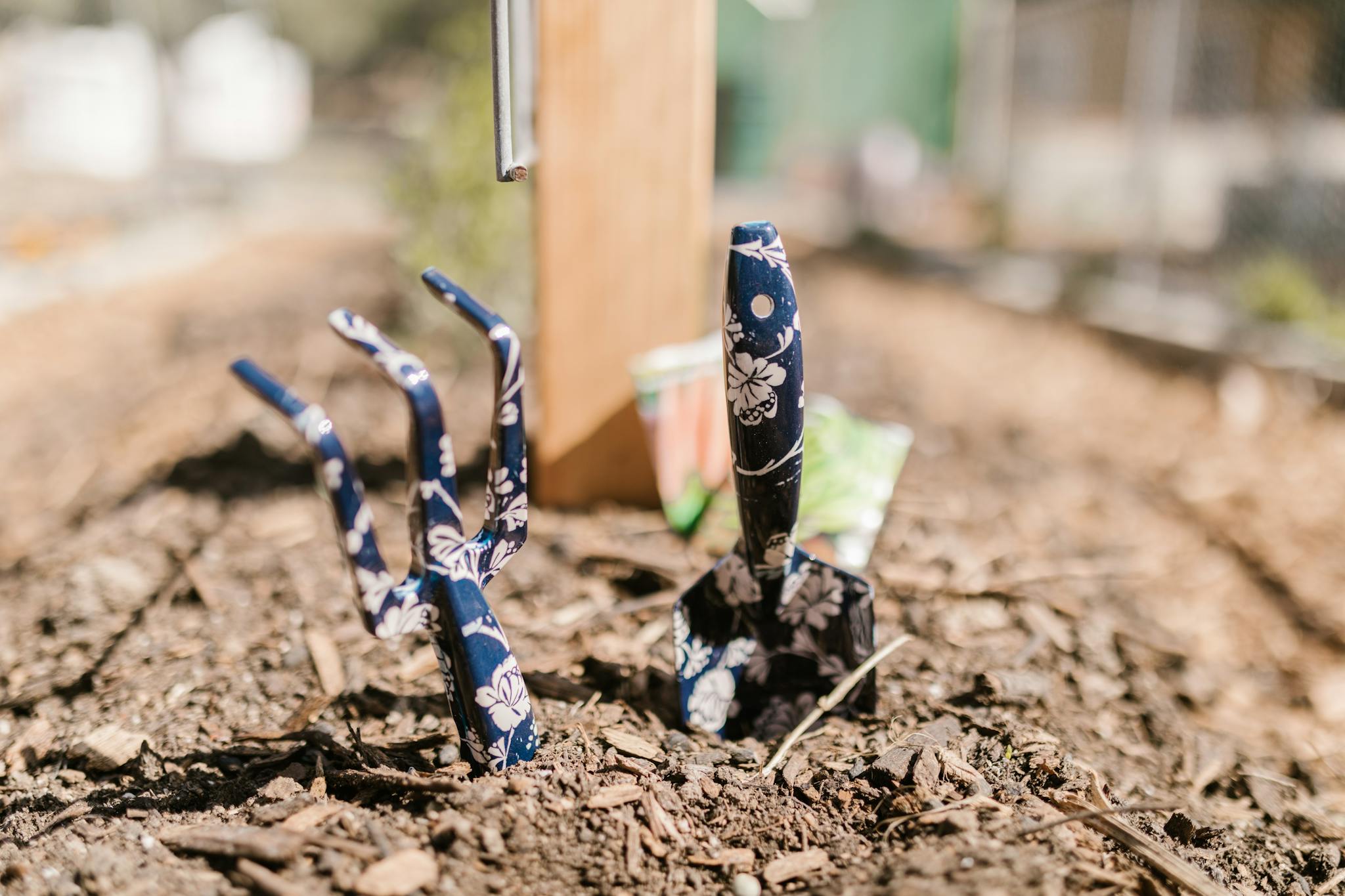 A vibrant close-up of floral-patterned gardening tools in fresh soil, capturing the essence of gardening.