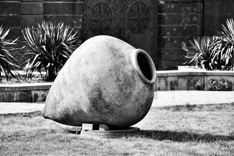 Large traditional Georgian wine pot on grass in a cultural setting.
